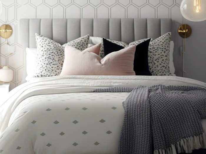 Comforter of bed features geometric pattern and accent pillows.